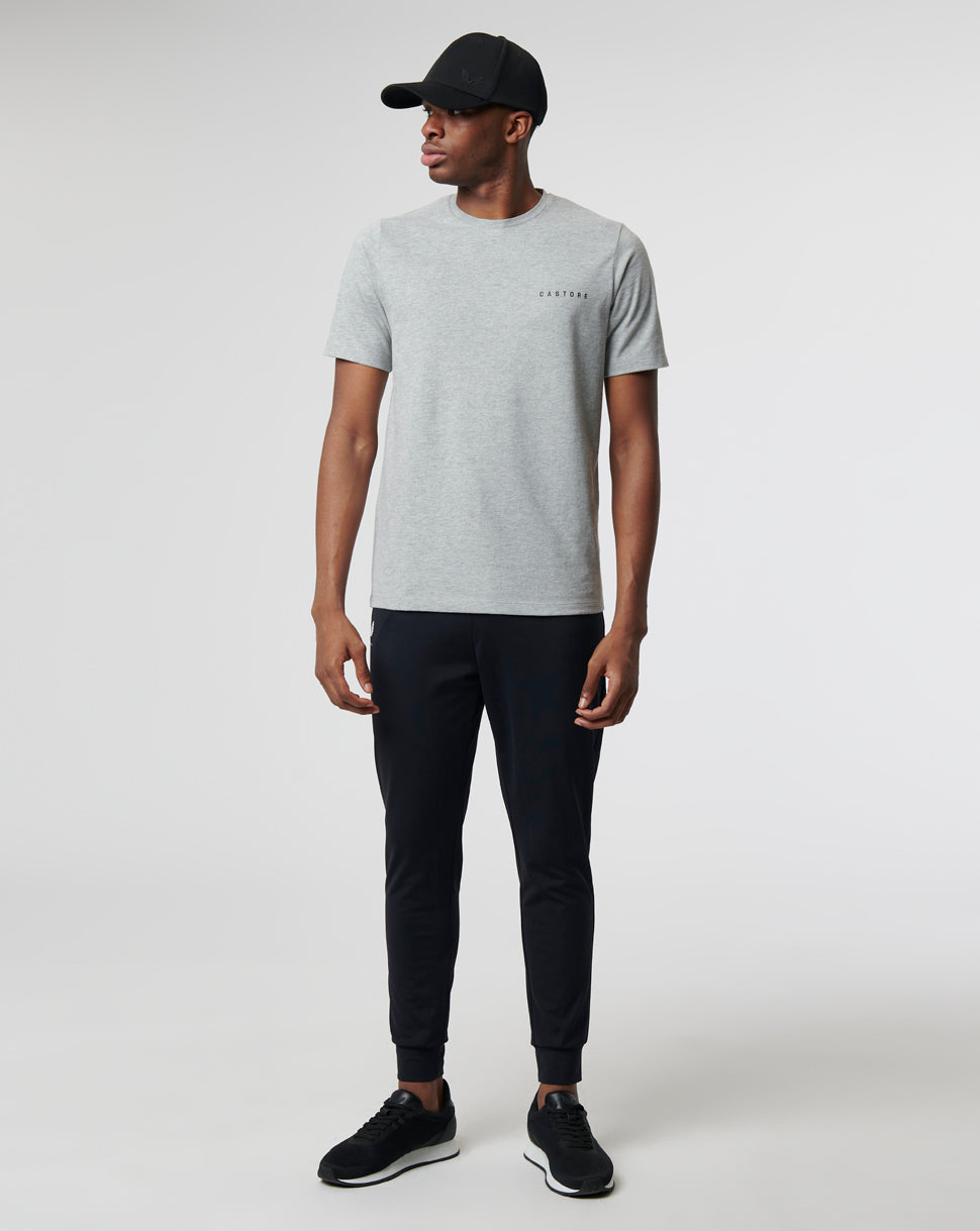 Model wearing a grey Sharkskin Marl Carbon Capsule Recovery T Shirt with Castore lettering on the chest and dark pants