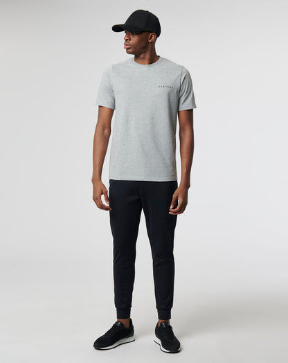 Model wearing a grey Sharkskin Marl Carbon Capsule Recovery T Shirt with Castore lettering on the chest and dark pants