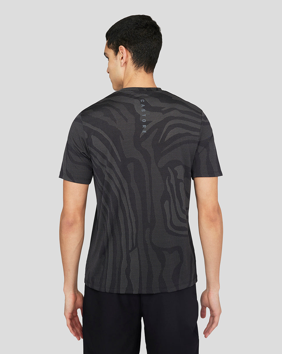 Back view of a man wearing a black Core Tech T-Shirt with an abstract zebra-like pattern and vertical branding down the spine.