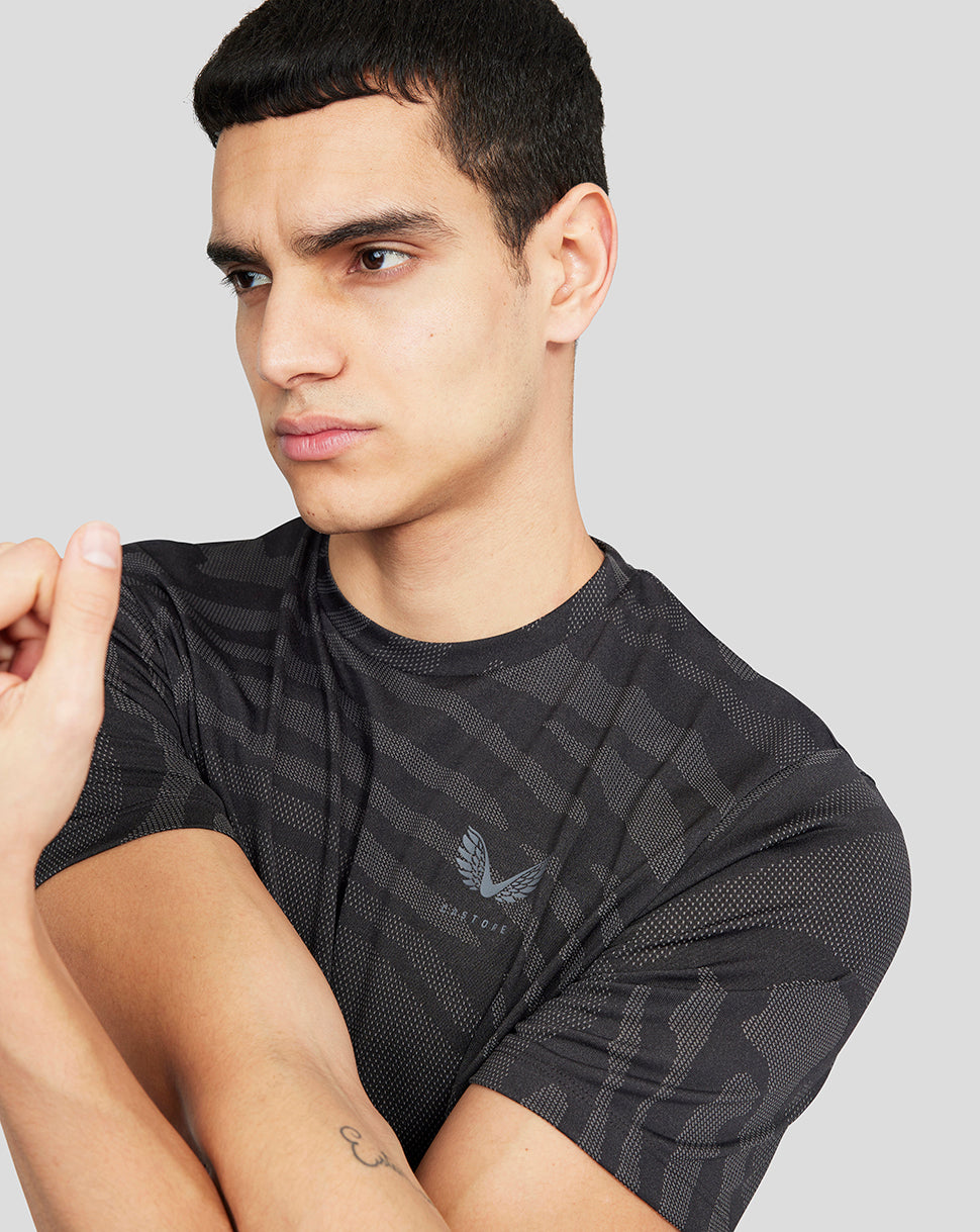 Close-up of a man modeling the Core Tech T-Shirt showing the chest logo against the dark patterned fabric.