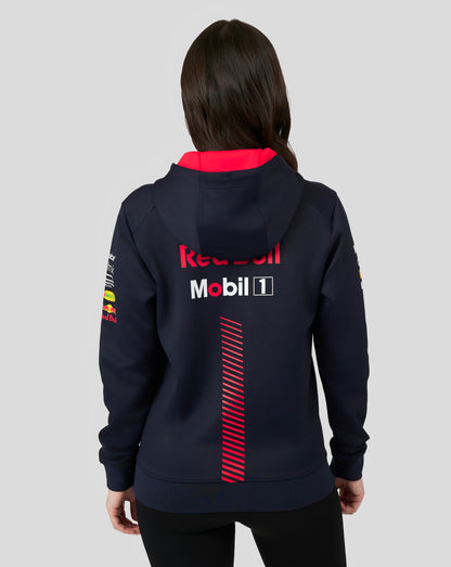 Female model in a navy Red Bull Racing full zip hoodie seen from the back with red interior and a large Red Bull logo; front pocket logos visible.
