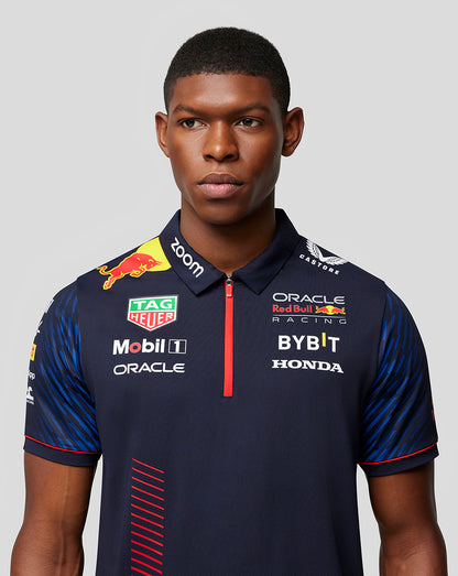 Male model wearing a Night Sky navy Castore x Oracle Red Bull Racing polo with sponsor logos and a red zip placket.