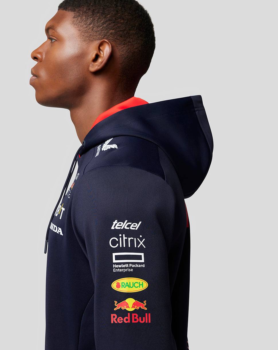 Side profile of a man in a navy Red Bull Racing hoodie showing logos on the sleeve and hood.