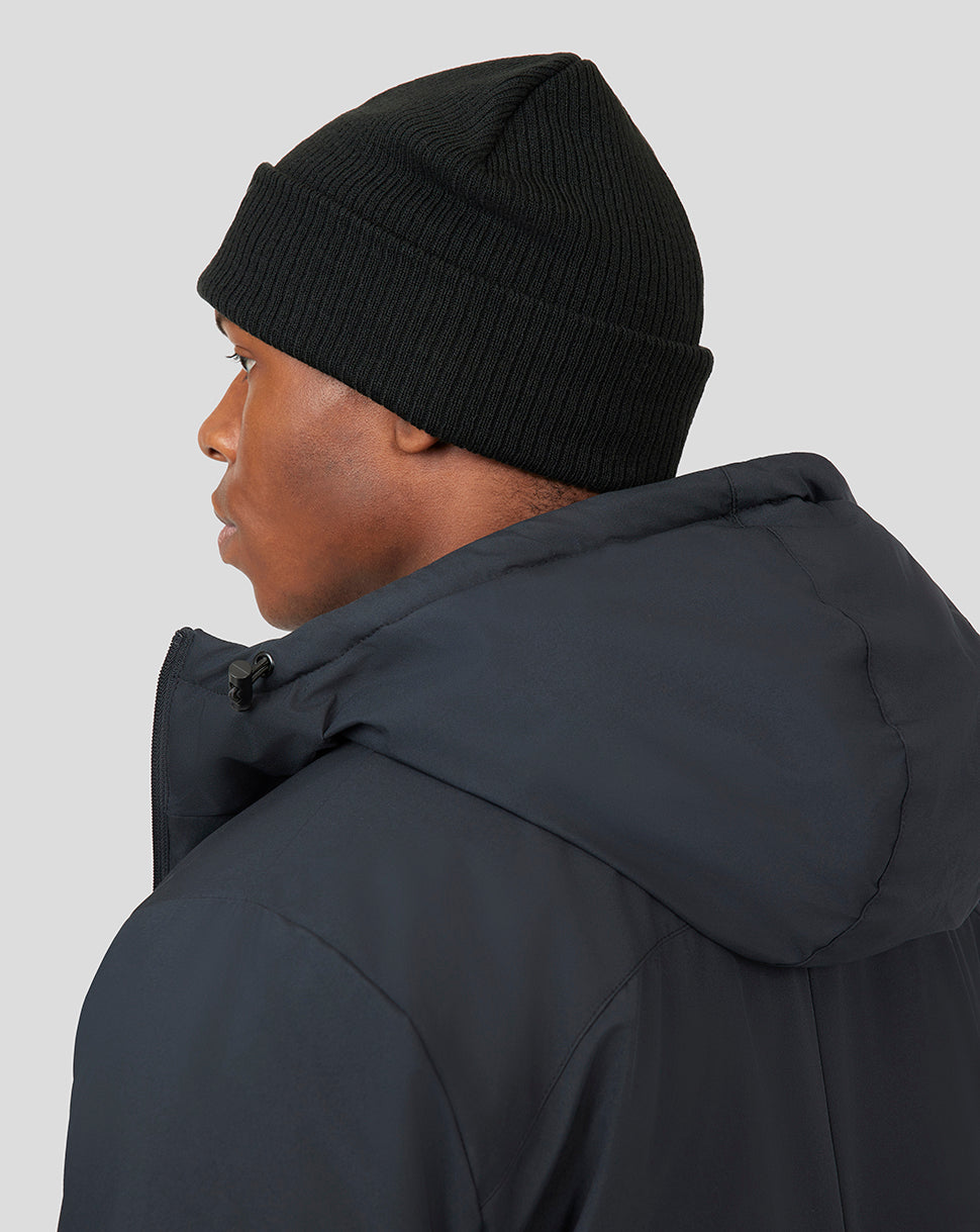 Side profile of a person wearing a black knit Active Beanie with a dark padded jacket.