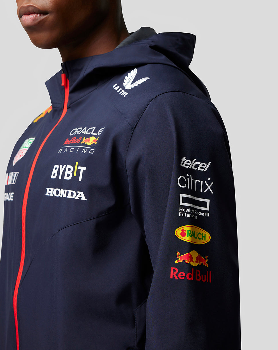 Side view of a model in navy water resistant Red Bull Racing jacket showing sponsor logos on the chest and sleeve