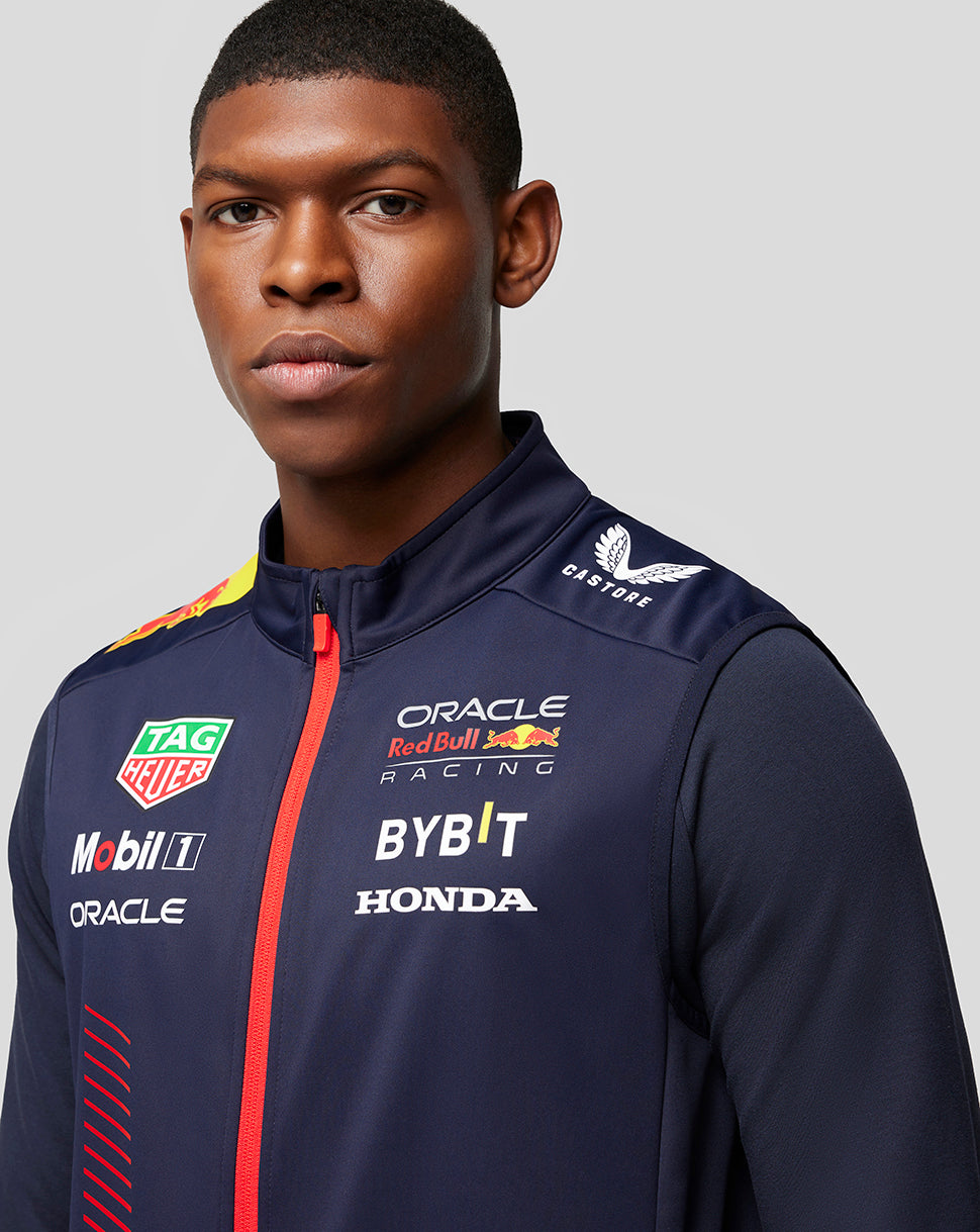 Shoulder close-up of navy gilet showing the yellow Red Bull emblem and racing sponsor branding.