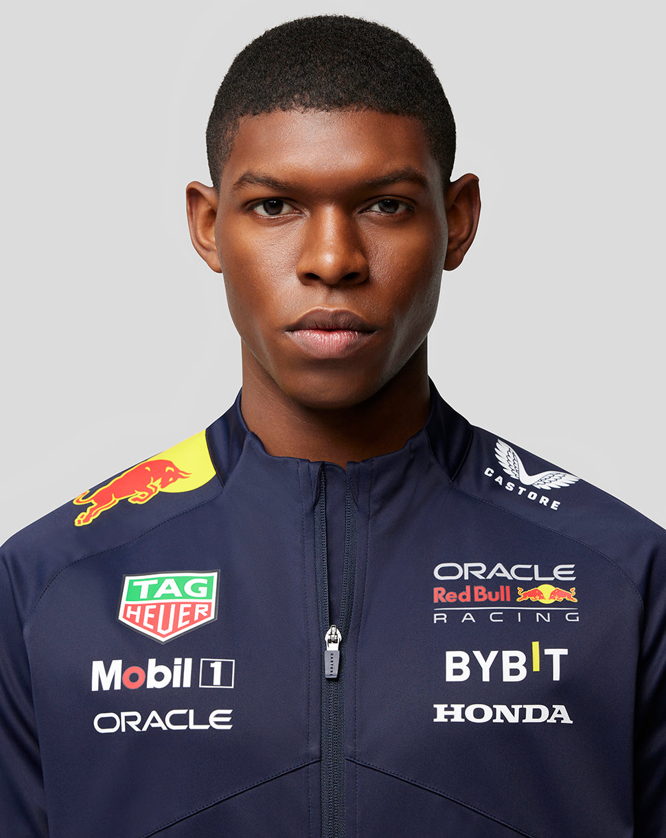Front close-up of a male model wearing a navy Oracle Red Bull Racing soft shell jacket with sponsor logos on the chest