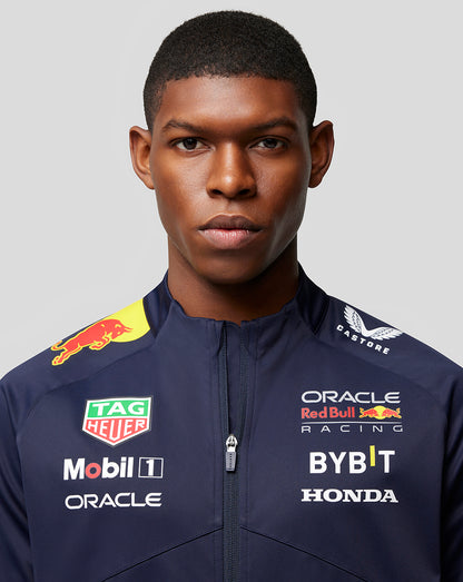 Front close-up of a male model wearing a navy Oracle Red Bull Racing soft shell jacket with sponsor logos on the chest