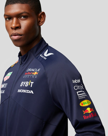 Side view of navy Red Bull Racing jacket on a model with sponsor logos across chest and sleeve