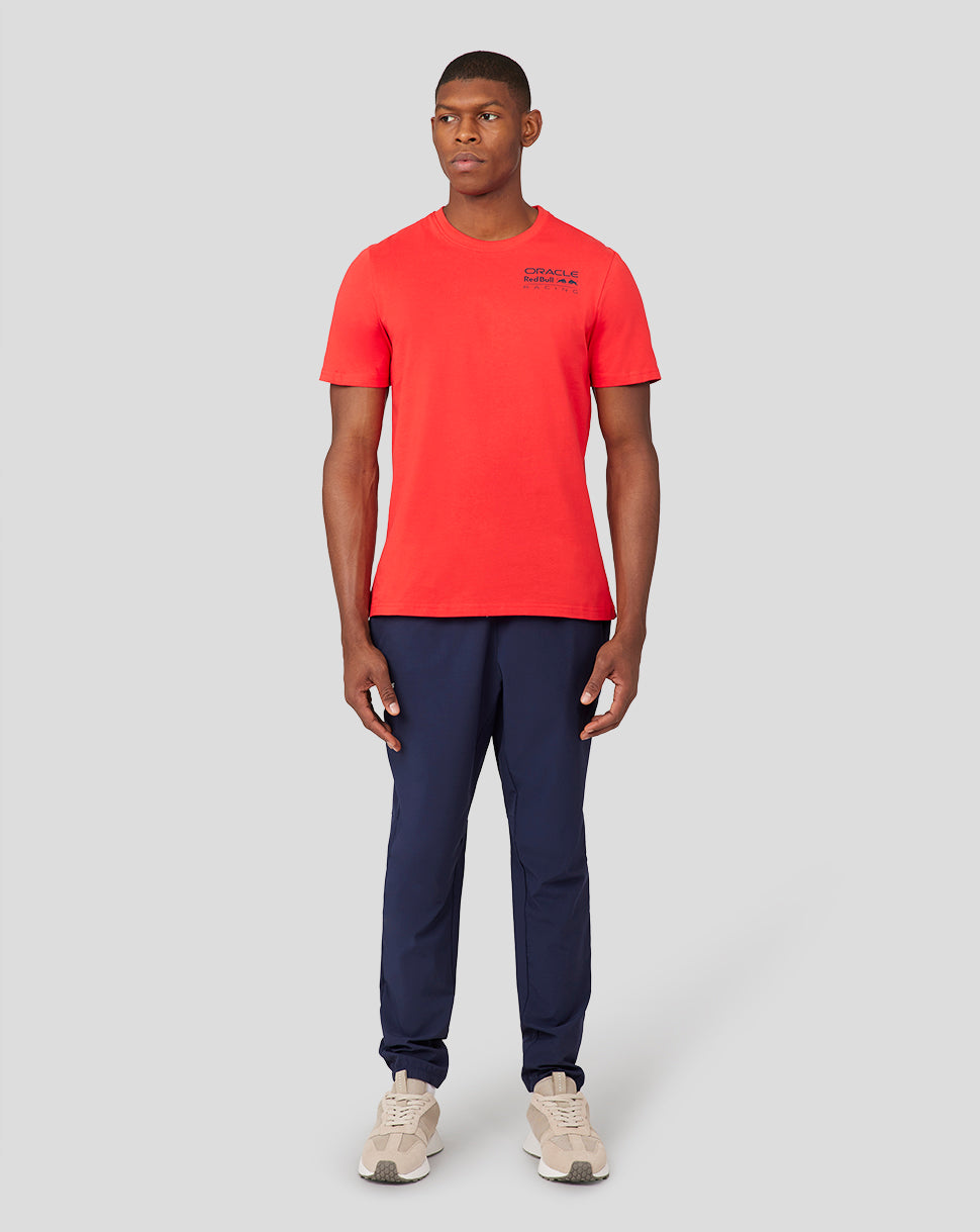 Full body view of a male model wearing flame scarlet Oracle Red Bull Racing Core T shirt with chest logo and navy pants