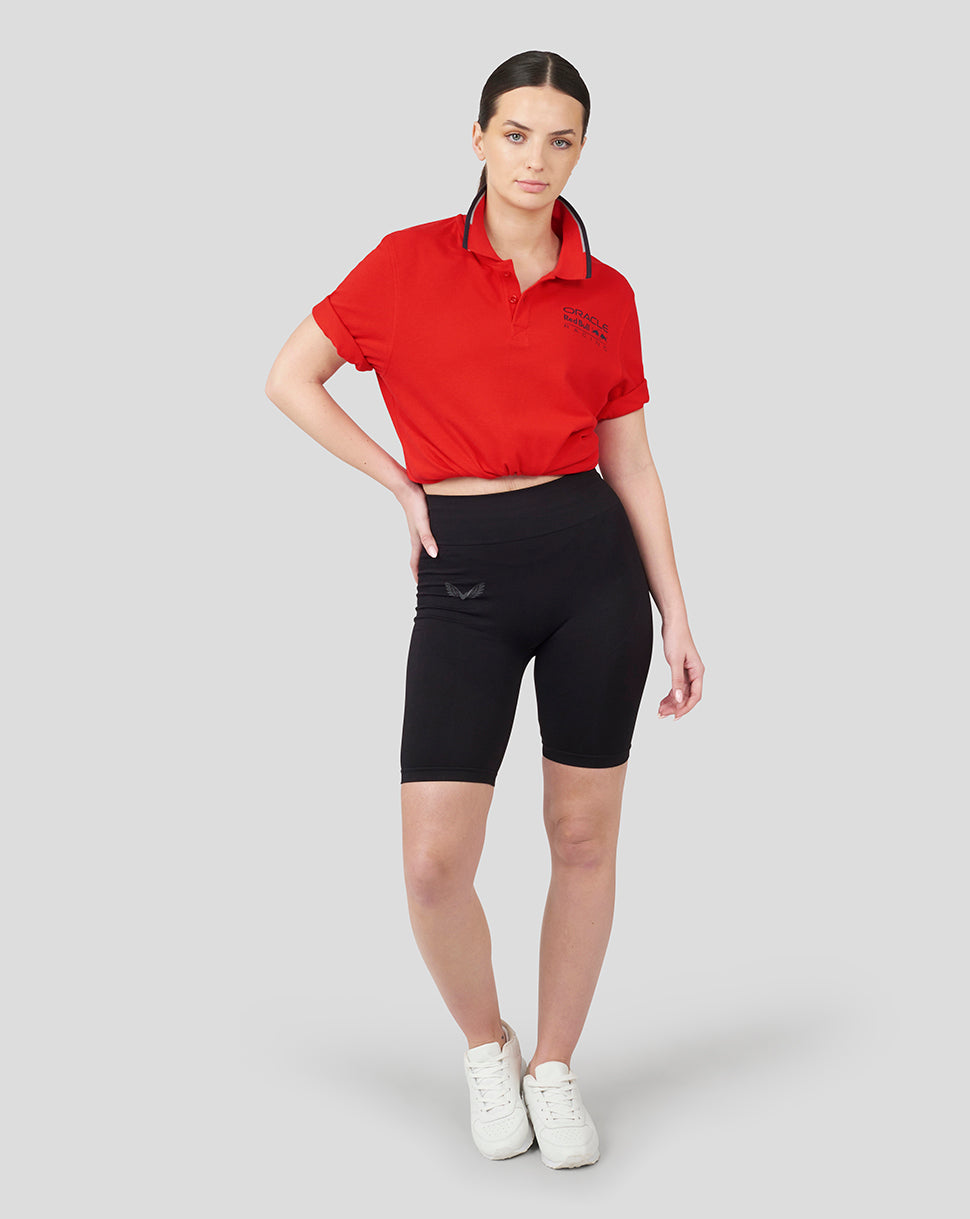 Front view of a woman wearing a cropped flame scarlet Core Polo with chest logo and navy trim.