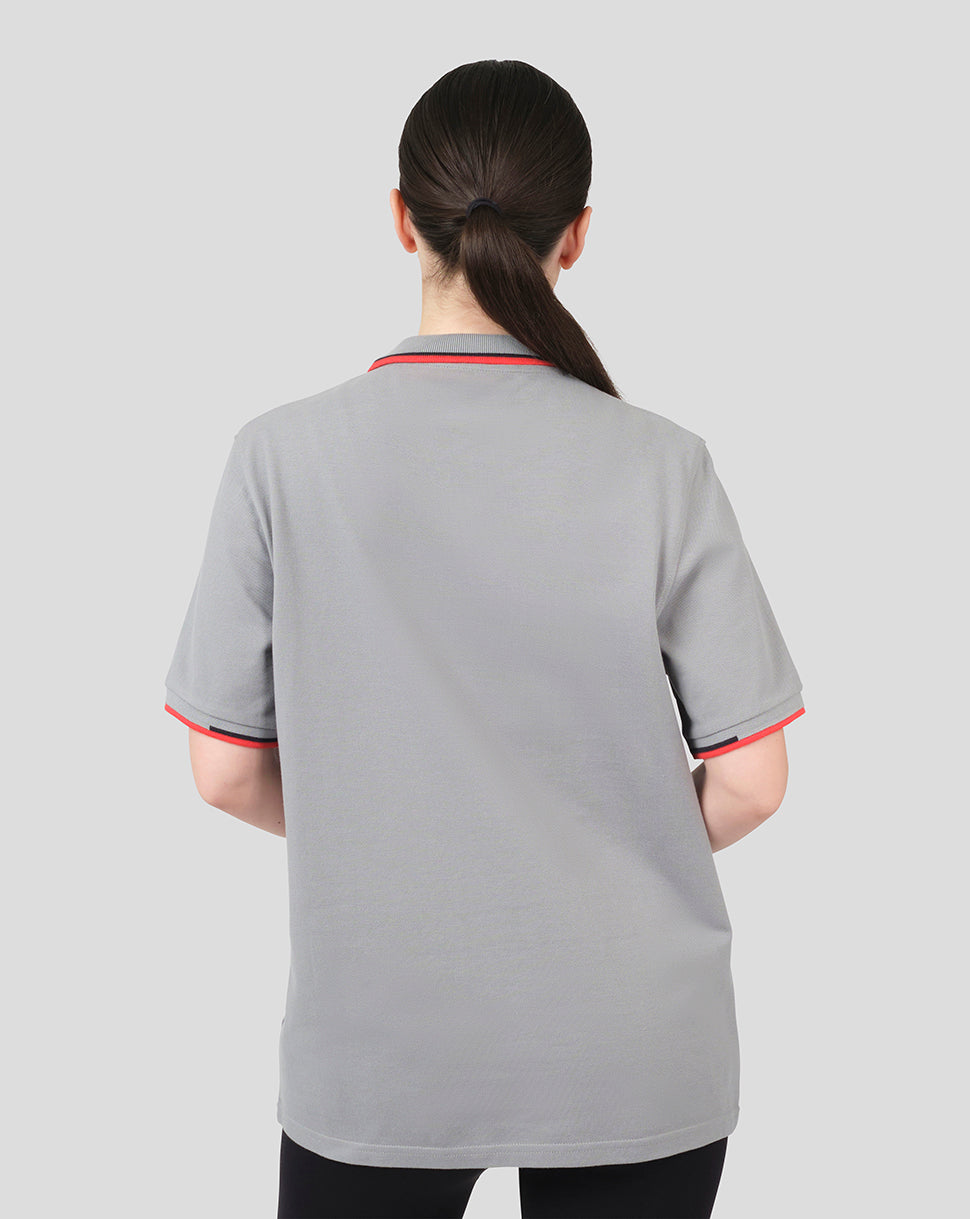 Back view of a woman in a grey Oracle Red Bull Racing Core Polo with red trim on collar and cuffs.
