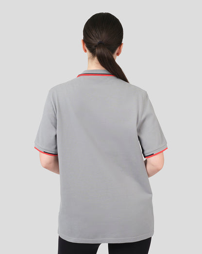 Back view of a woman in a grey Oracle Red Bull Racing Core Polo with red trim on collar and cuffs.