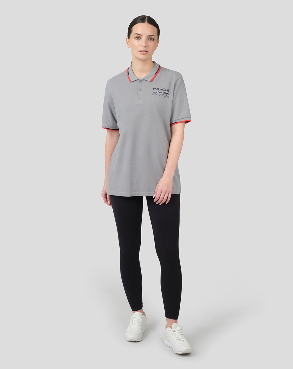 Full length shot of a woman in a grey Oracle Red Bull Racing polo with red piping and chest logo.