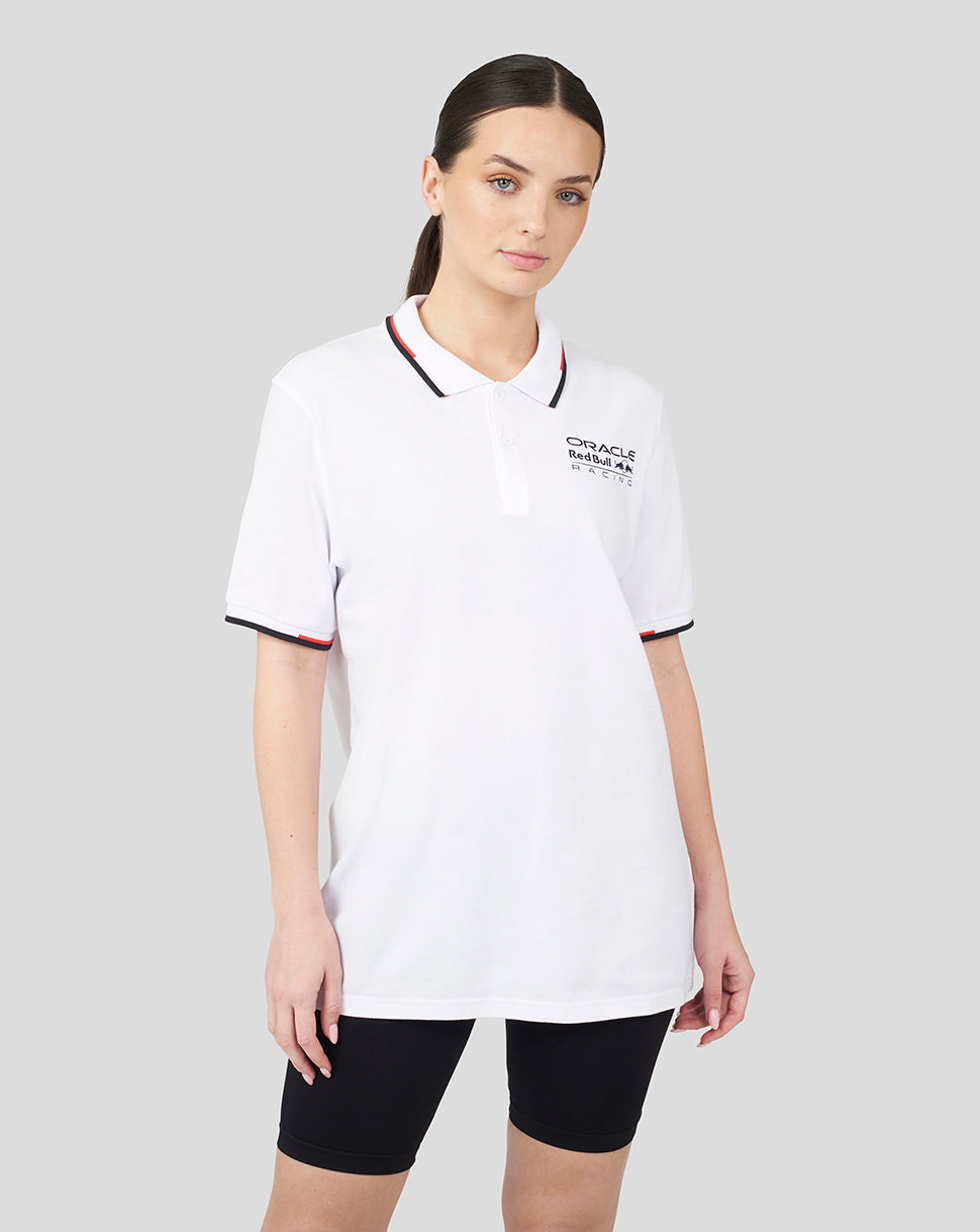 Female model wearing white Oracle Red Bull Racing Core Polo with logo on the chest and red black tipped collar.