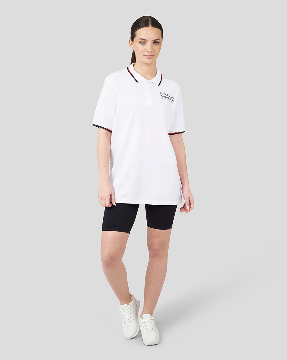 Female model wearing white Oracle Red Bull Racing Core Polo with chest logo and striped collar; black shorts