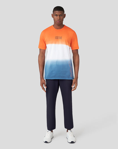 Full-body view of a male model wearing the Exotic Orange Oracle Red Bull Racing Verstappen T shirt with an orange to white to blue dip-dye gradient