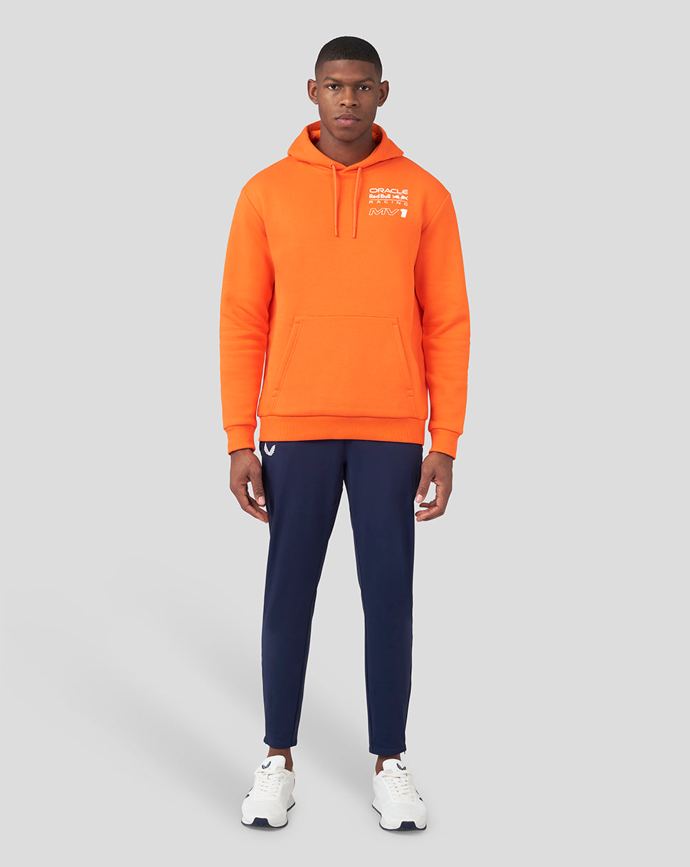Full-body shot of a man in an orange Oracle Red Bull Racing hoodie with navy pants.