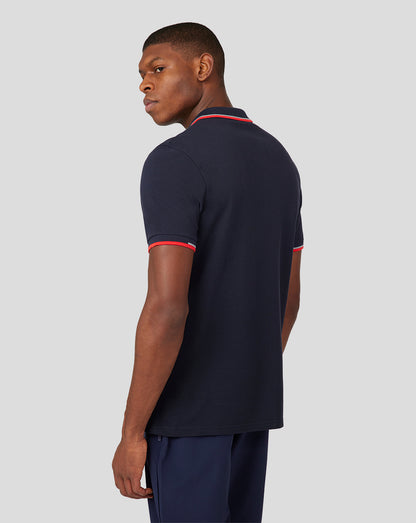 Side view of a male model wearing a navy Oracle Red Bull Racing Unisex Core Polo with red trim on collar and sleeves
