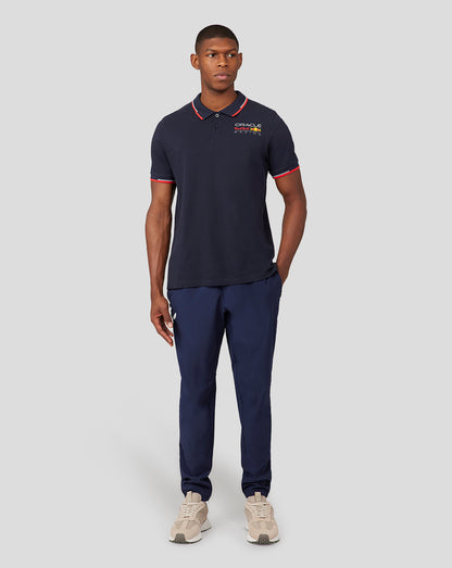 Male model in navy Oracle Red Bull Racing polo with left chest logo paired with navy pants and beige sneakers