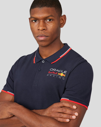 Male model wearing navy Oracle Red Bull Racing polo with left chest logo and red tipped collar
