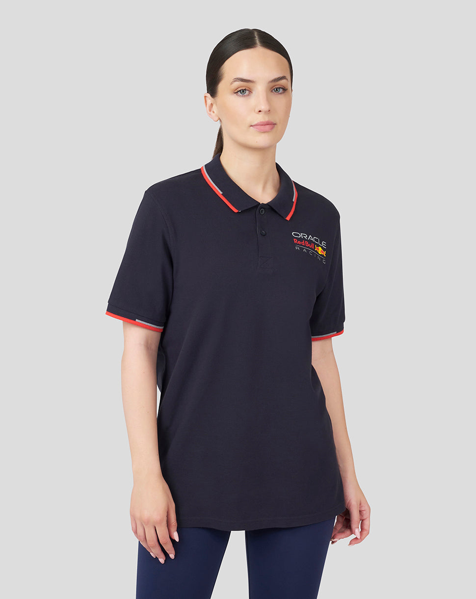 Front view of a model wearing a navy Oracle Red Bull Racing Unisex Core Polo with red tipped collar and sleeve cuffs and left chest logo