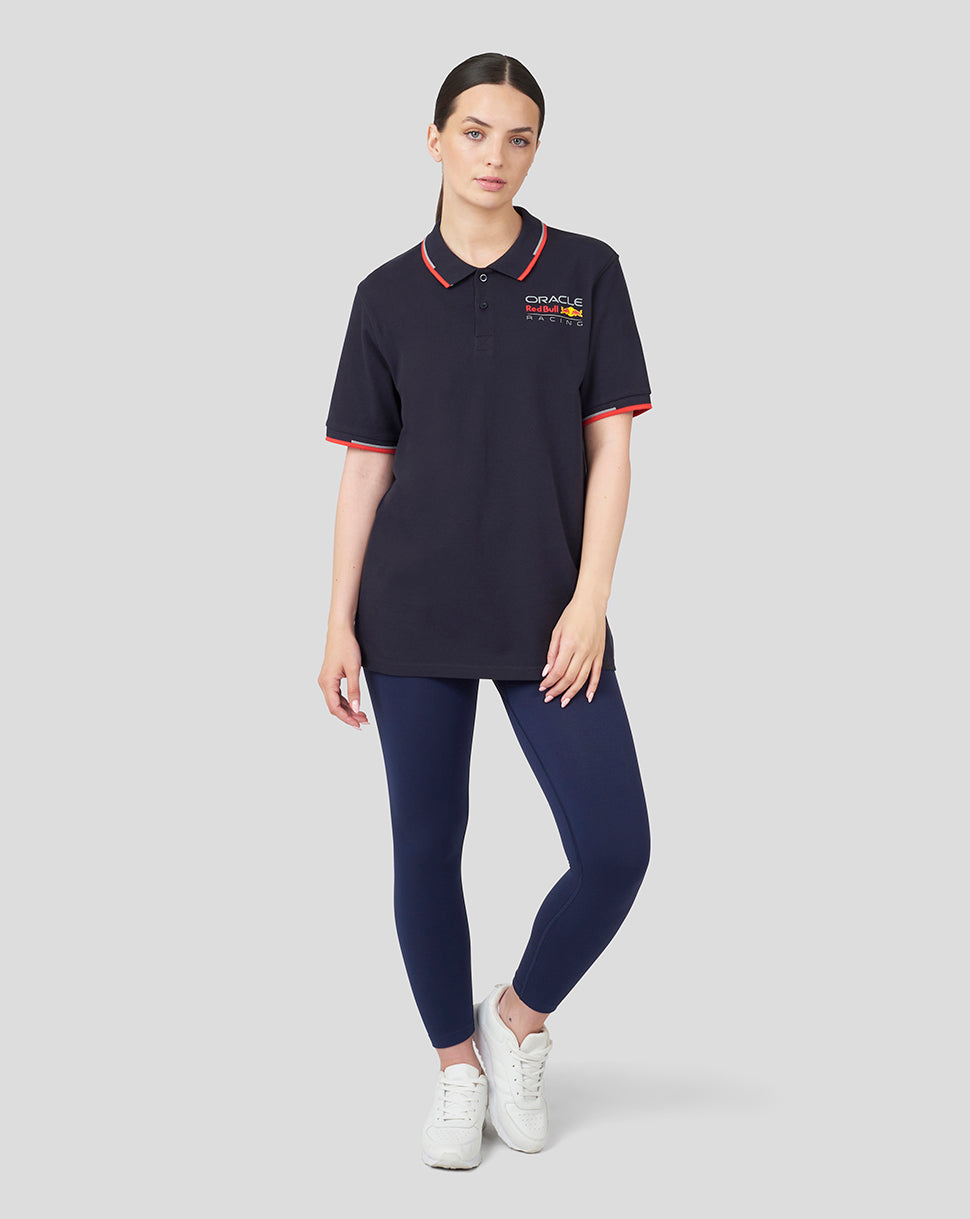 Model wearing navy Oracle Red Bull Racing unisex core polo with red collar and sleeve trim, left chest logo.