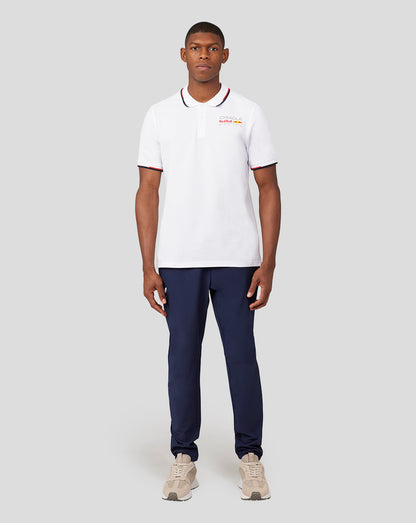 Male model in white Oracle Red Bull Racing Core Polo with left chest logo, paired with navy pants.
