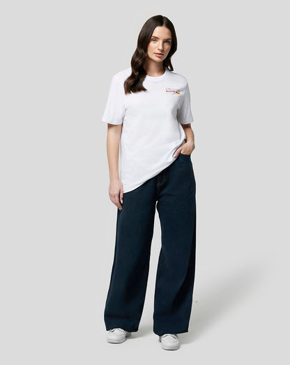 Woman in white Oracle Red Bull Racing Core T Shirt with full colour left chest logo and navy pants, hand in pocket.